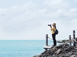 Obraz premium Young girl traveler taking photographs of summer beach.