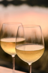 A romantic dinner in summer on a beach at sunset with two glasses of white wine