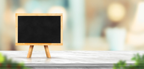 Blackboard on white marble table and blurred soft light table in luxury restaurant with bokeh...