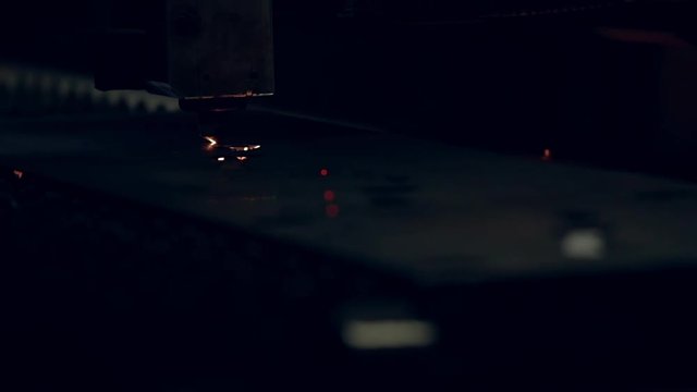 Modern programmed robot head cuts metal with sparks.