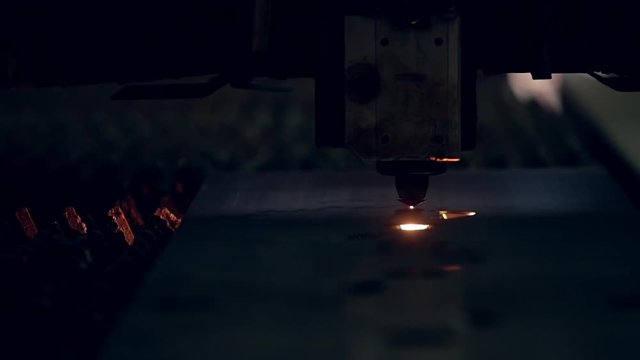 Modern programmed robot head cuts metal with sparks.