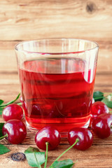 Fresh cherry juice and cherry berries on wooden table.