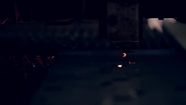 Modern programmed robot head cuts metal with sparks.