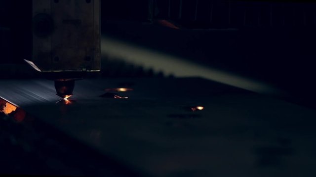 Modern programmed robot head cuts metal with sparks.