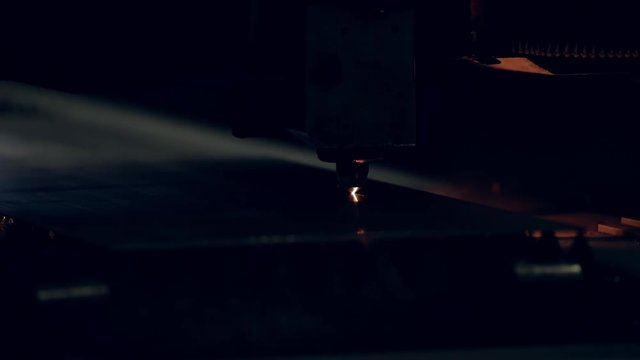 Modern programmed robot head cuts metal with sparks.