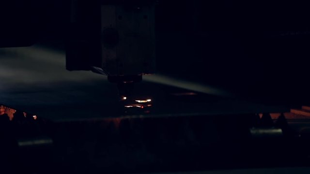 Modern programmed robot head cuts metal with sparks.