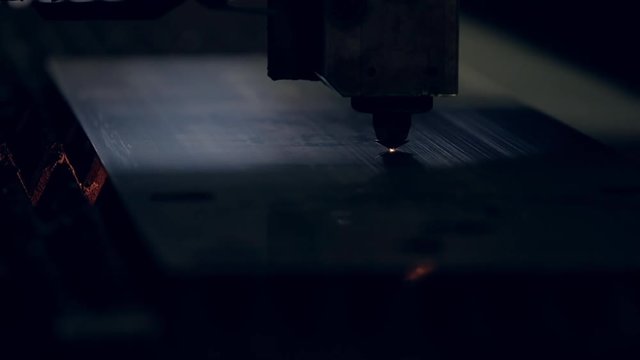 Modern programmed robot head cuts metal with sparks.