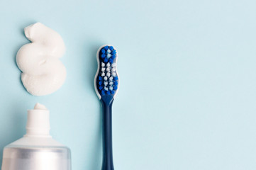 Toothpaste in tube and toothbrush on blue background. Dental hygiene concept.