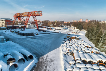 Open warehouse for storage of large diameter metal pipes. A gantry crane is installed in the...