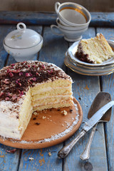 Delicious coconut layer cake - biscuit and cream on coconut cream, decorated with grated chocolate and candied rose petals.