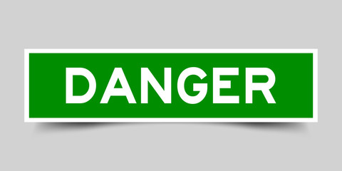 Square green danger sticker label in word  on gray background