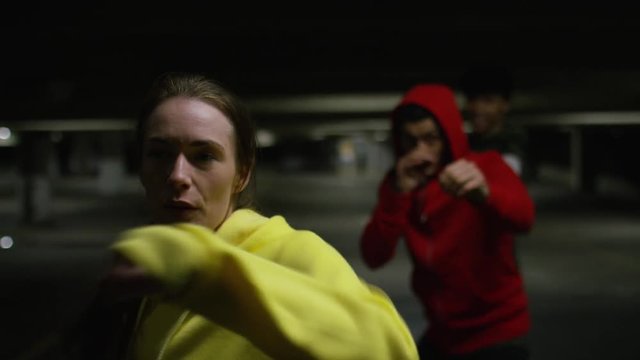 Camera moves across urban boxing training class, in slow motion
