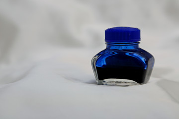 A small half full ink bottle on a white background