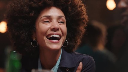 beautiful woman with afro hairstyle hanging out with friends in restaurant laughing enjoying conversation socializing at party gathering