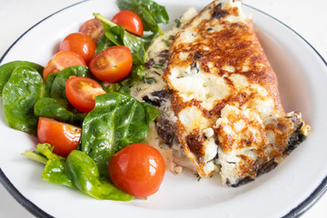 Omelet with mushrooms, salad with cherry tomatoes and spinach, on a light background. Healthy eating concept. Close-up.