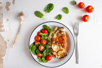 Omelet with mushrooms, salad with cherry tomatoes and spinach, on a light background. Healthy eating concept.