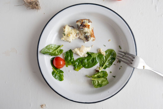 Leftover Food On A Plate, Close-up And On A Light Wooden Background.