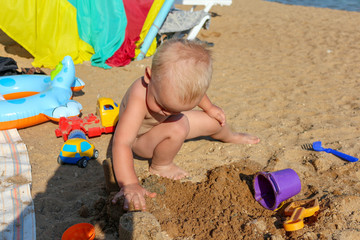 the kid plays on the beach on a sunny summer day, he builds something out of the sand