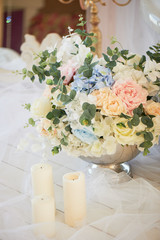 Floor metal vase with flowers and white candles. Romantic atmosphere