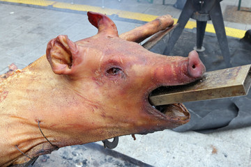 A young pig head is fried on coals in a street restaurant
