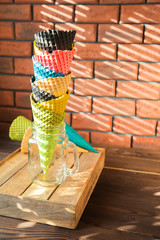 Multicolored ice cream cones in a jar close-up and copy space. Cones for ice cream on a background of textural red brick wall.