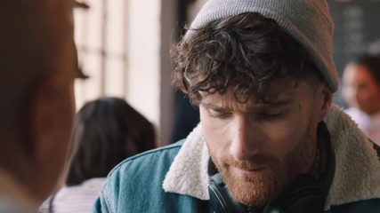 attractive hipster man chatting with friend drinking coffee in cafe socializing enjoying conversation relaxing in restaurant