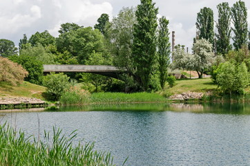 Spring panorama of a part of residential district, bridge and Thermoelectric power plant neighborhood along a lake with green trees, shrubs, flowers, Drujba, Sofia, Bulgaria  