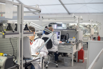 People wearing white coats sitting in the laboratory at the computers and conduct experiments