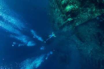 Freediver man make bubbles at underwater shipwreck, Bali