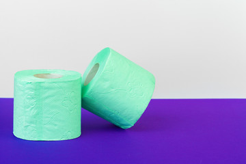 Toiletries. Rolls of green toilet paper on purple background