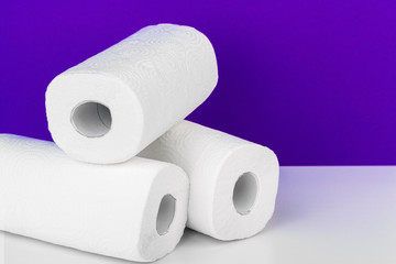 Roll of paper towel on table against purple background