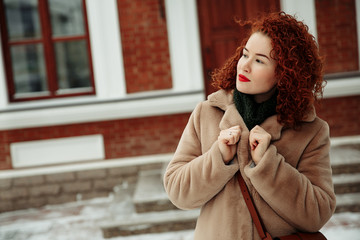 Blissful ginger girl having fun in cold winter day. Emotional red-haired woman posing with snow.