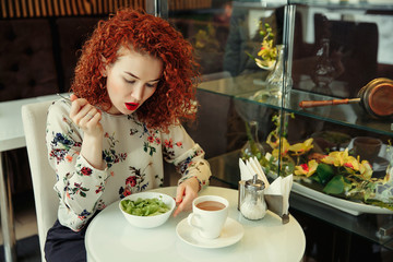 A young attractive woman sitting in a cafe with a salad