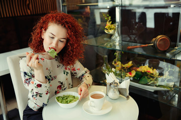 A young attractive woman sitting in a cafe with a salad