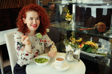 A young attractive woman sitting in a cafe with a salad