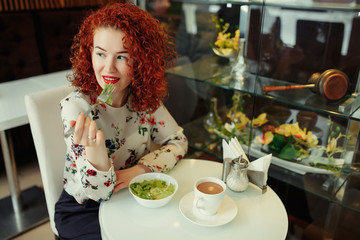 A young attractive woman sitting in a cafe with a salad