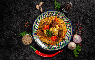 The concept of oriental cuisine. National Uzbek pilaf with meat in a cast-iron skillet, on a wooden...