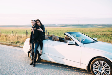 Sympathetic couple husband and wife spend time outside the city, sitting on a car hood