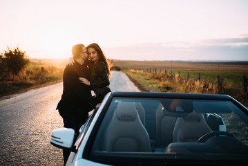 Sympathetic couple husband and wife spend time outside the city, sitting on a car hood