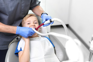 Dziecko u stomatologa.  Leczenie zęba, stomatolog czyści ubytek - obrazy, fototapety, plakaty