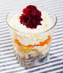 verrin with salad herring under fur coat from vegetables on striped tablecloth