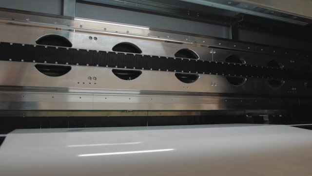 Details of a moving print head. Massive machinery. Professional  printing facility, big vinyl rolls, ready for export. Glossy, matte, ecological materials used for commercial billboards and press.
