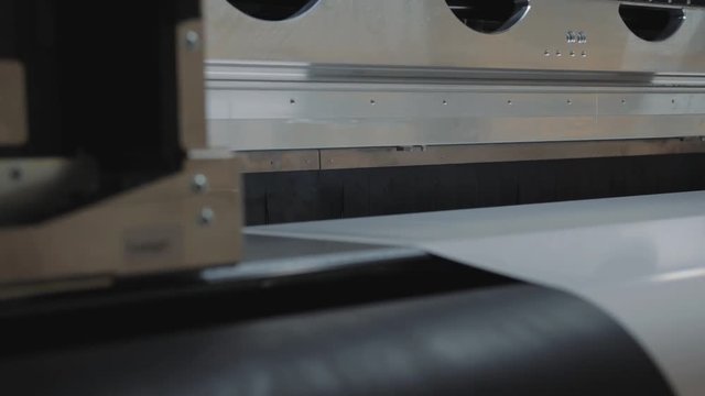 Details of a moving print head. Massive machinery. Professional  printing facility, big vinyl rolls, ready for export. Glossy, matte, ecological materials used for commercial billboards and press.