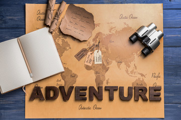 Binocular, scrolls, notebook and world map on wooden background. Travel concept