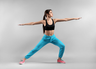 Sporty young woman on light background