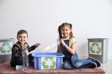 Little children sorting garbage near white wall. Concept of recycling