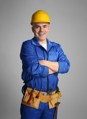 Mature worker in uniform on grey background