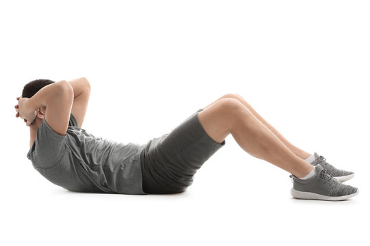 Sporty young man doing crunches against white background