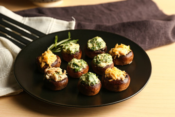 Plate with tasty stuffed mushrooms on table