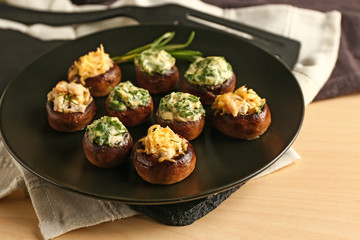 Plate with tasty stuffed mushrooms on table